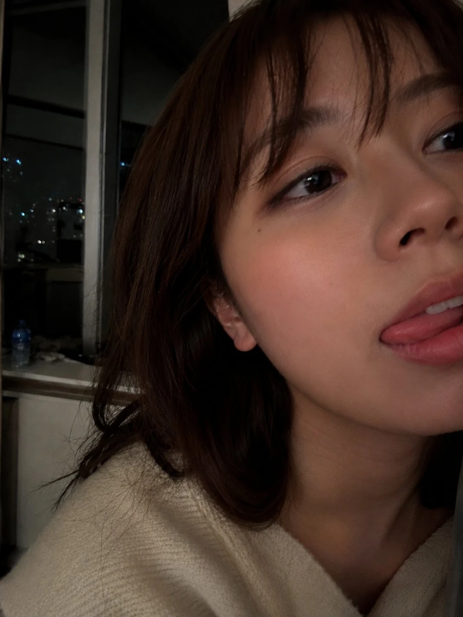 Ultra-realistic close-up selfie portrait of a young woman indoors at nigh...