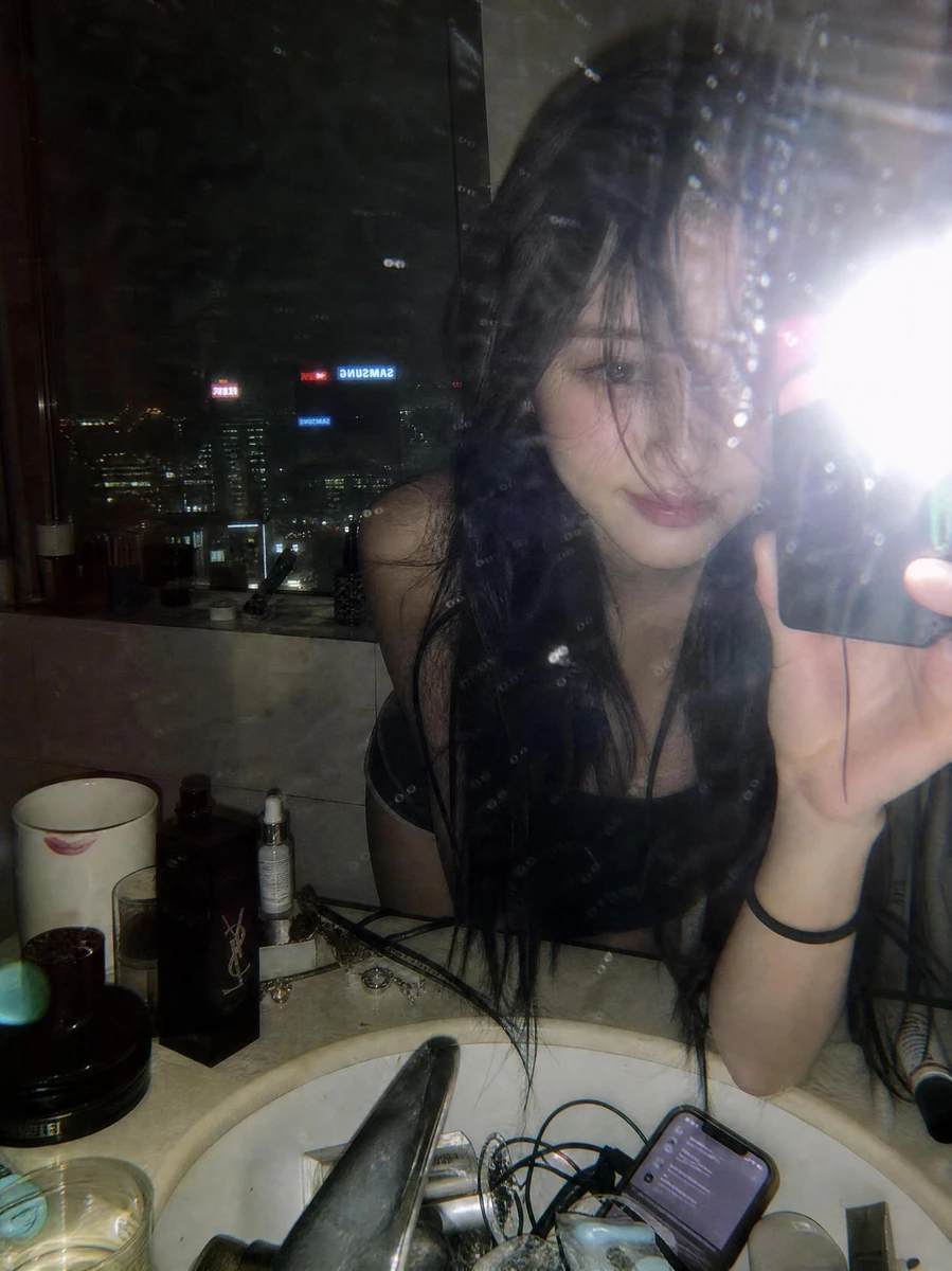 A moody late-night mirror selfie captured in a luxury high-rise bathroom...