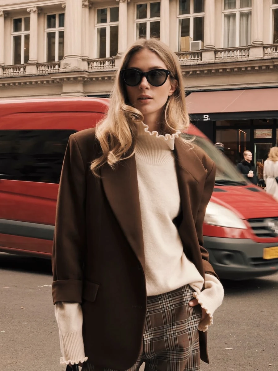 A high-fashion street style photoshoot of a blonde woman wearing oversize...