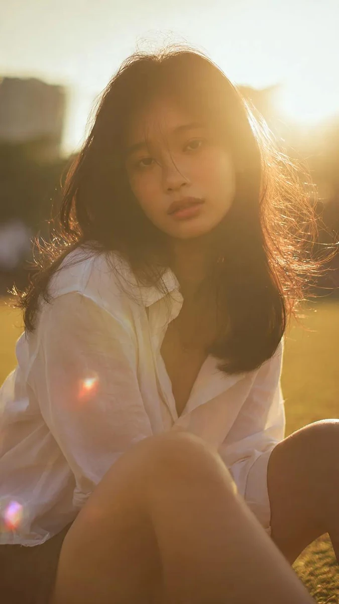 Cinematic portrait of a young asian woman sitting on grass outdoors, soft...