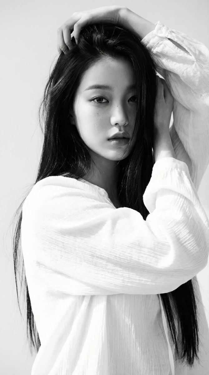 Black-and-white portrait of a young woman with long straight dark hair, w...