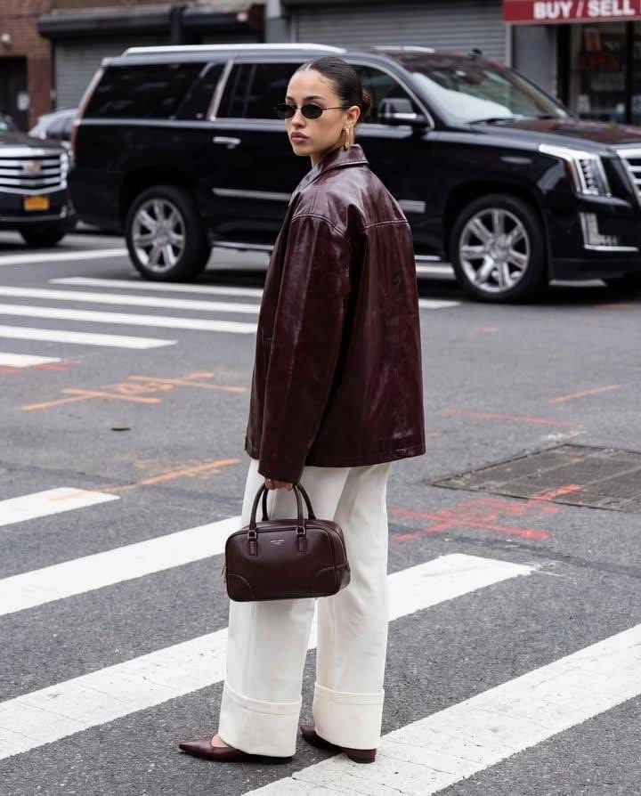 Candid street-style fashion photograph of a confident woman crossing a ci...