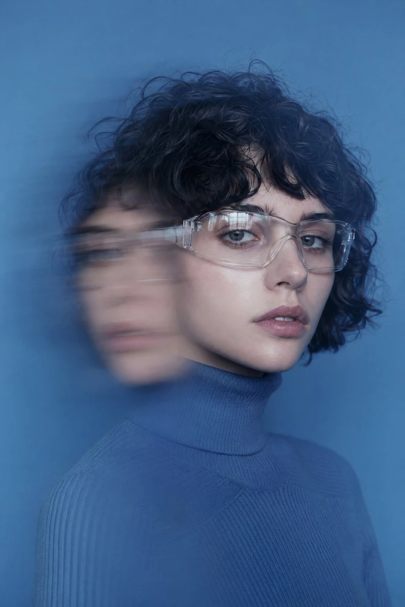 portrait of a young woman with short curly black hair and fair skin, wear...