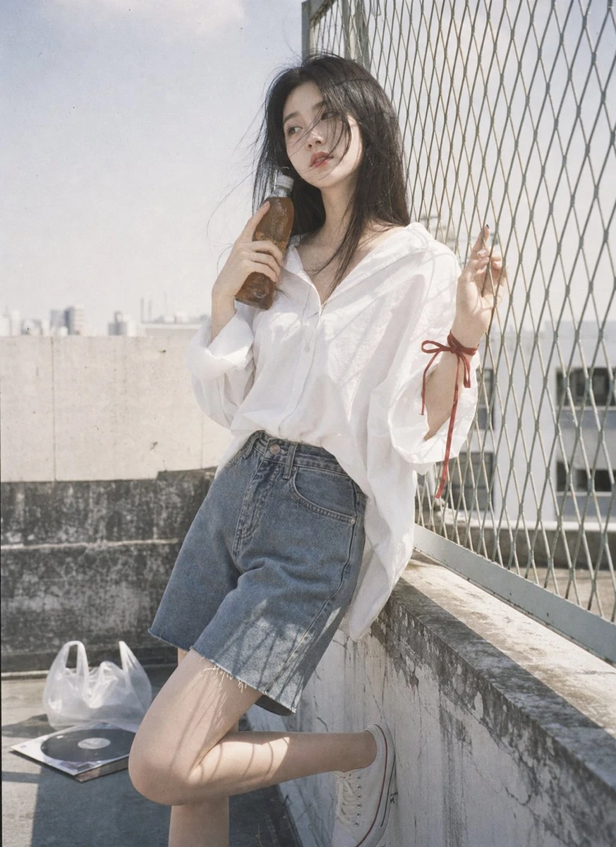 Rooftop corner beside a small chain-link fence, open sky, pale concrete w...