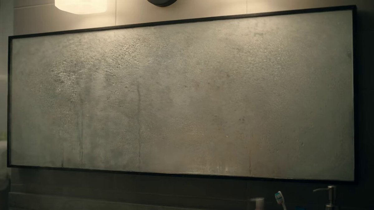 A bathroom mirror covered in heavy steam. A hand has wiped a single clear...