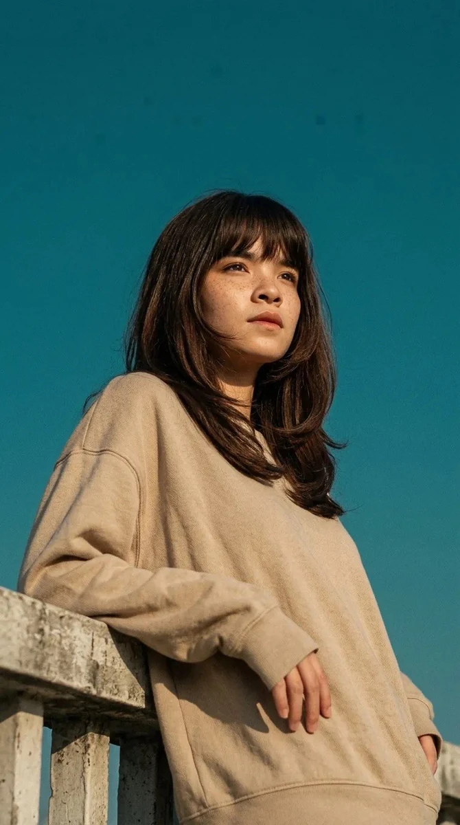Cinematic portrait of a young woman leaning on a concrete railing, wearin...