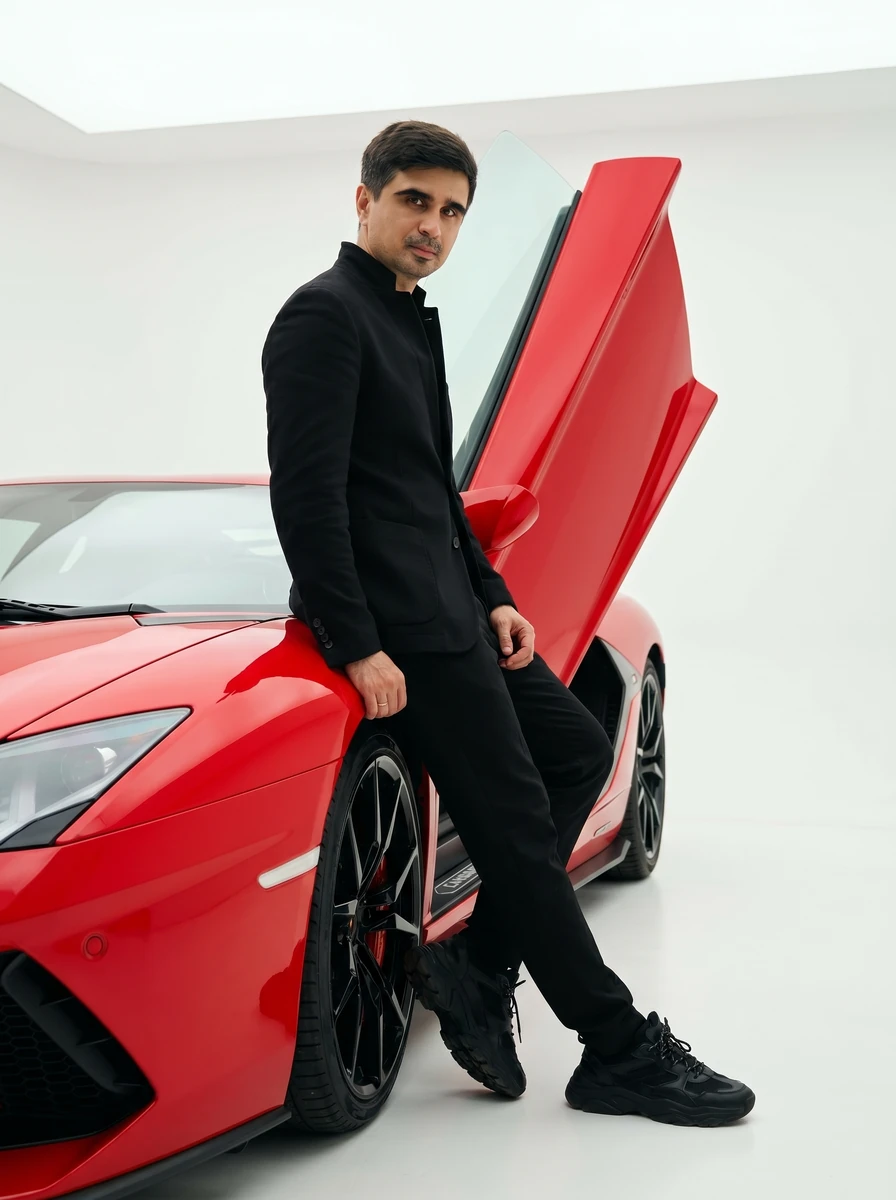 High-fashion editorial shot of a man leaning casually against the open sc...